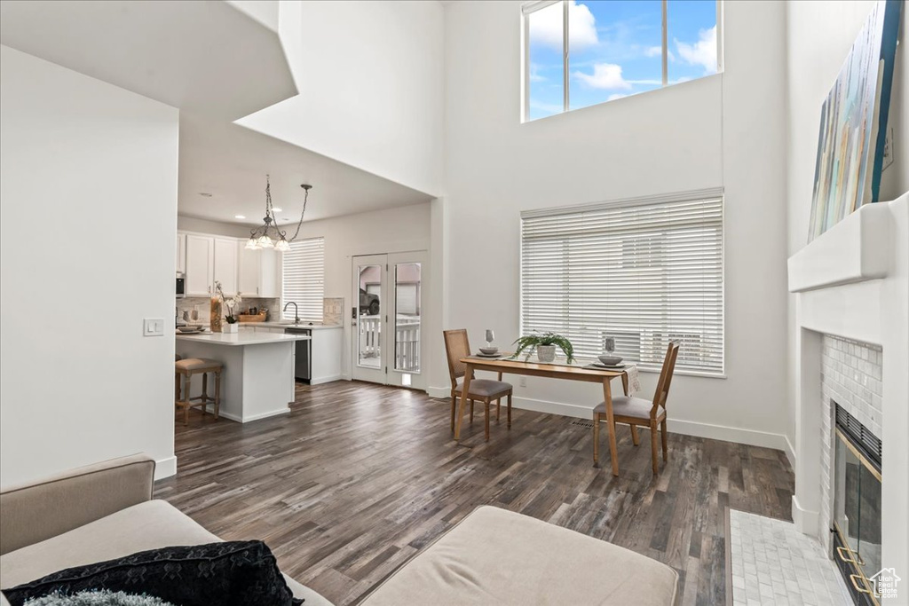 Living room featuring a fireplace, sink, a chandelier, a high ceiling, and dark wood-type flooring