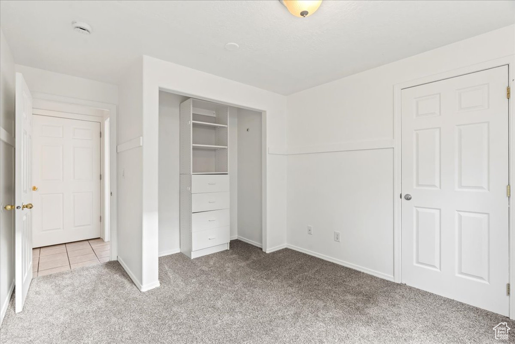 Unfurnished bedroom with a closet and light carpet