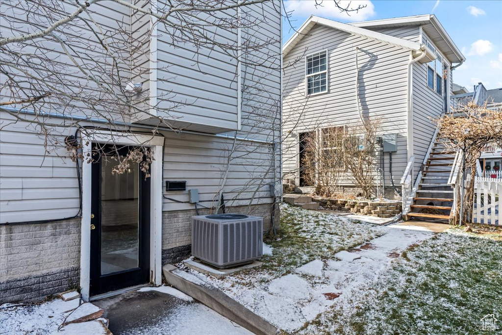 Snow covered back of property featuring central AC unit