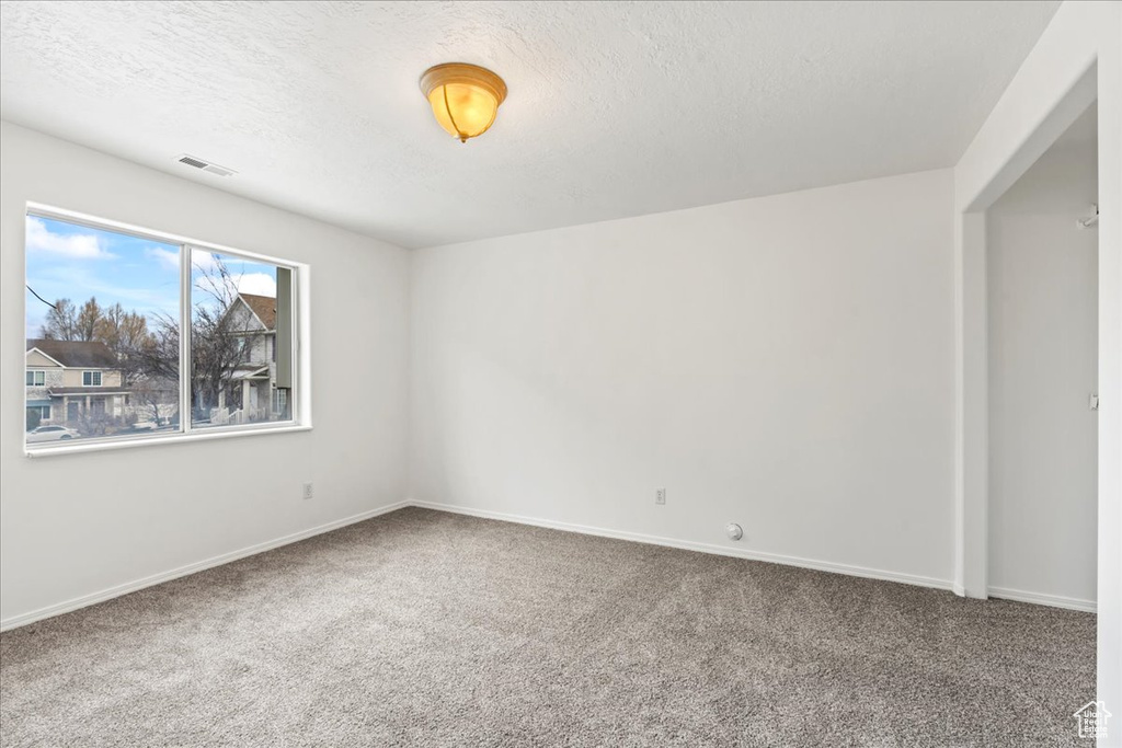 Carpeted empty room featuring a textured ceiling