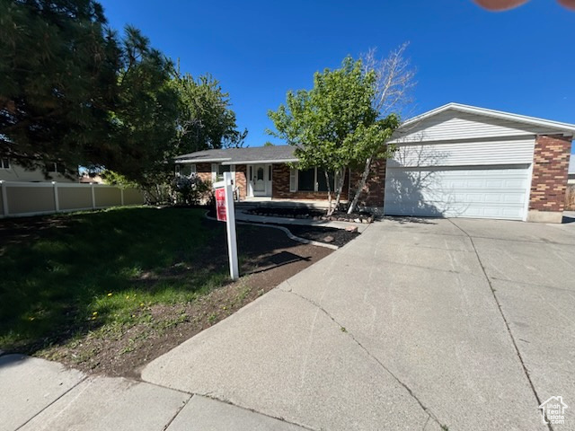 Single story home featuring concrete driveway, an attached garage, and brick siding
