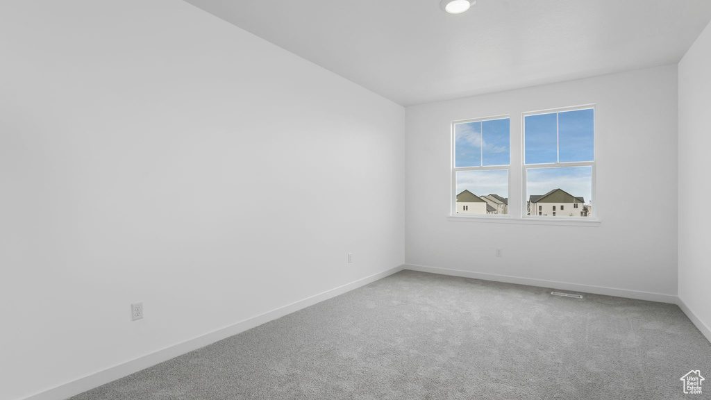 Carpeted empty room featuring baseboards and lofted ceiling