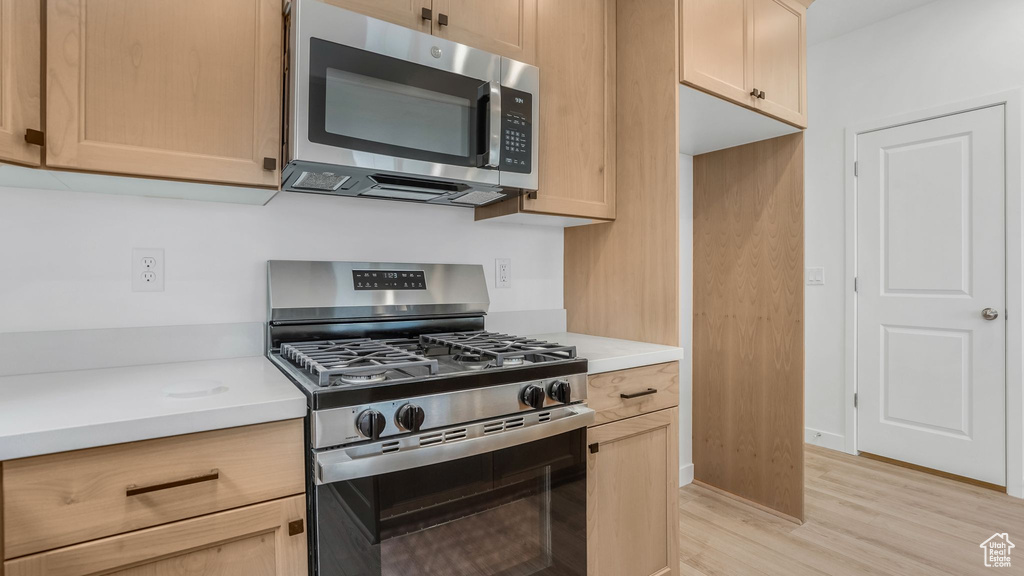 Kitchen featuring stainless steel appliances, light countertops, light wood finished floors, and light brown cabinets