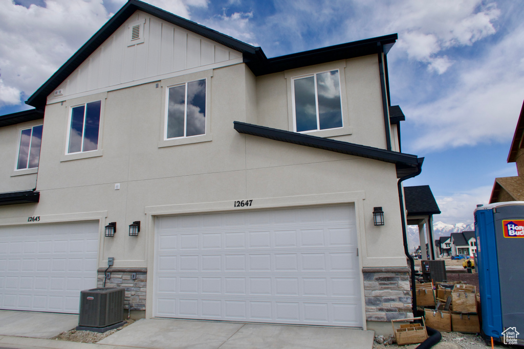 View of side of property with central air condition unit, stone siding, and stucco siding