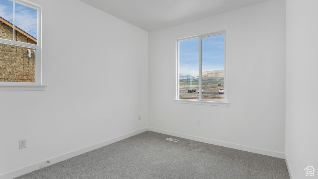 Carpeted spare room featuring baseboards