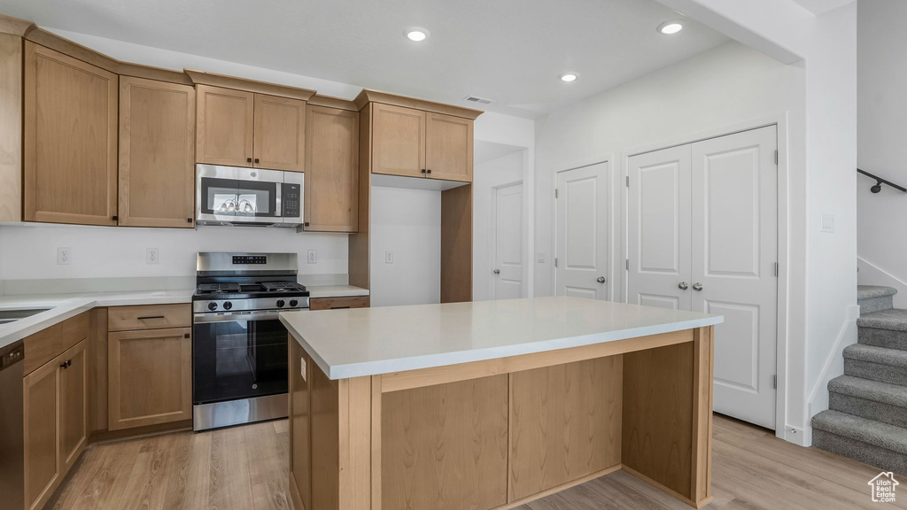 Kitchen featuring stainless steel appliances, light wood-style flooring, recessed lighting, light countertops, and a kitchen island