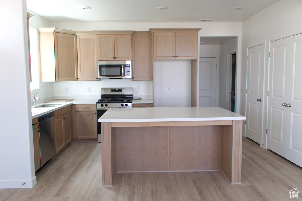 Kitchen with light wood-style flooring, appliances with stainless steel finishes, and light brown cabinets