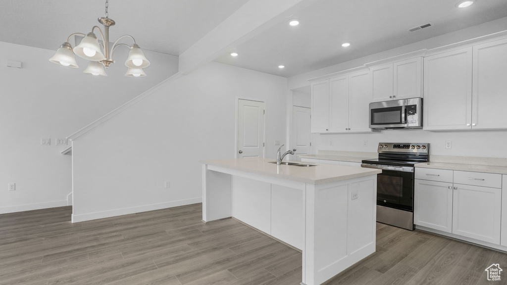 Kitchen featuring stainless steel appliances, light countertops, light wood-type flooring, a kitchen island with sink, and white cabinets