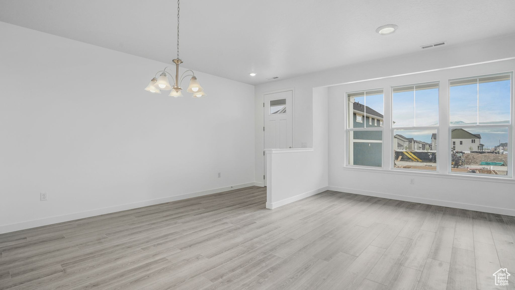 Spare room featuring a chandelier, light wood-type flooring, baseboards, and recessed lighting