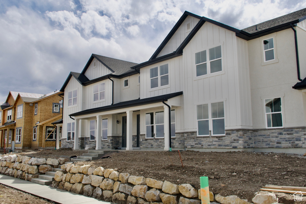 Rear view of house with a porch, board and batten siding, and stone siding