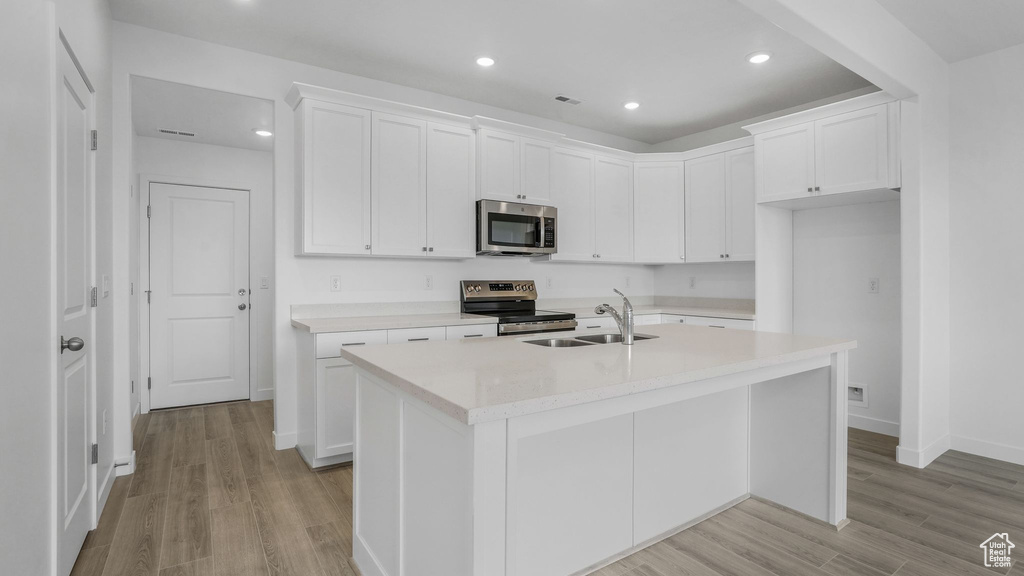 Kitchen featuring stainless steel appliances, light wood finished floors, baseboards, light countertops, and white cabinets