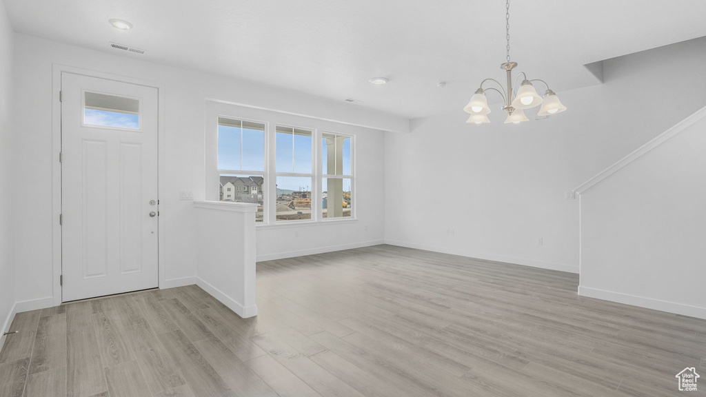 Entrance foyer featuring a chandelier, healthy amount of natural light, wood finished floors, and baseboards