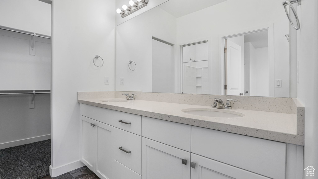 Bathroom featuring double vanity, a walk in closet, and baseboards