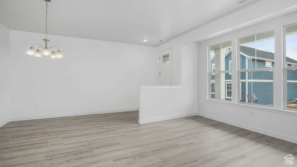 Spare room featuring a chandelier, light wood-type flooring, baseboards, and recessed lighting