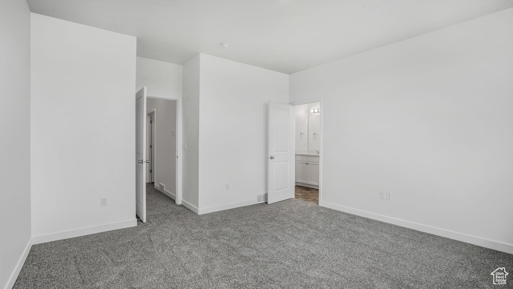Unfurnished bedroom featuring carpet flooring, baseboards, and ensuite bath