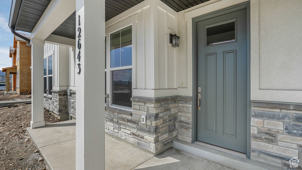 Property entrance featuring covered porch and stone siding