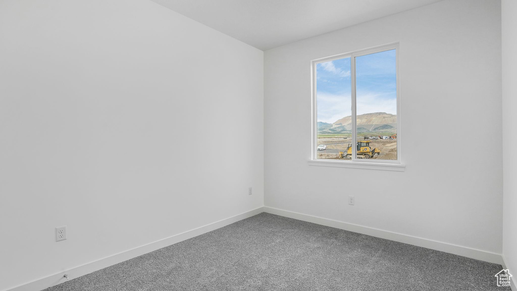Unfurnished room with baseboards, dark carpet, and a mountain view
