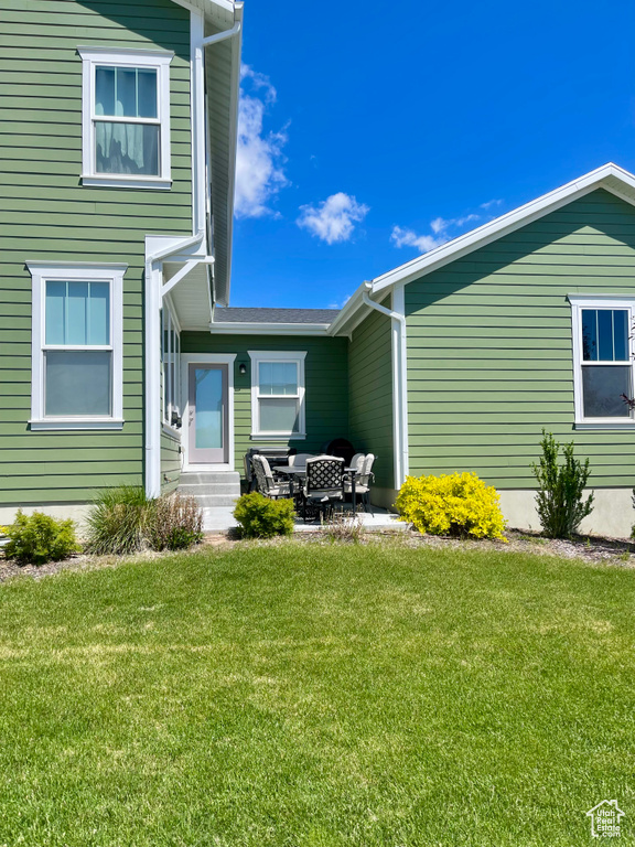 Back of property with entry steps and a yard