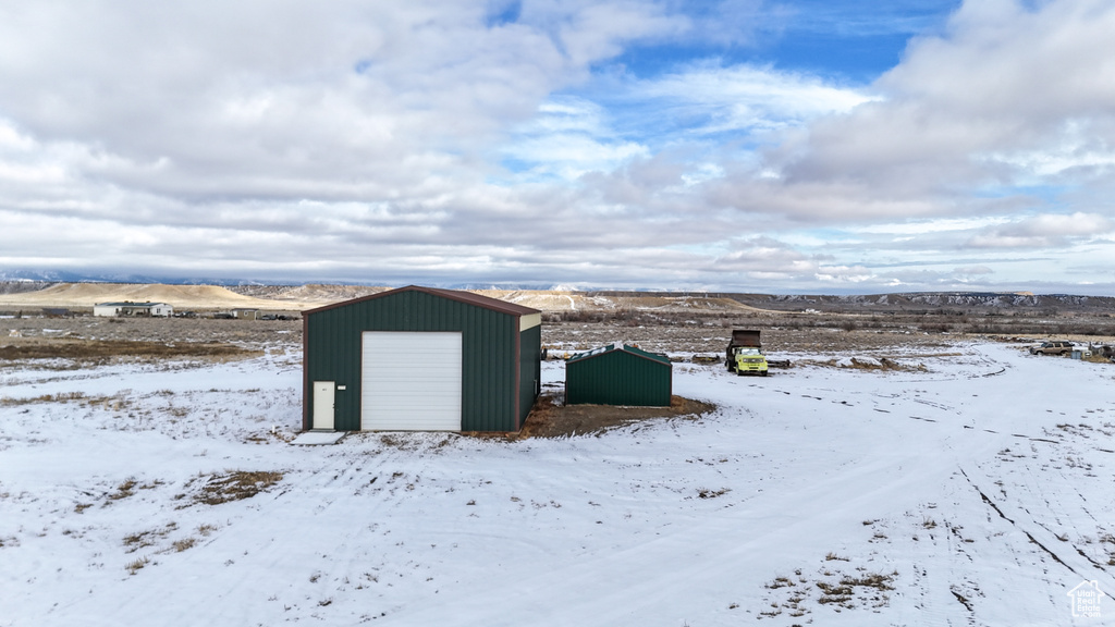 Snow covered structure featuring a mountain view and a garage