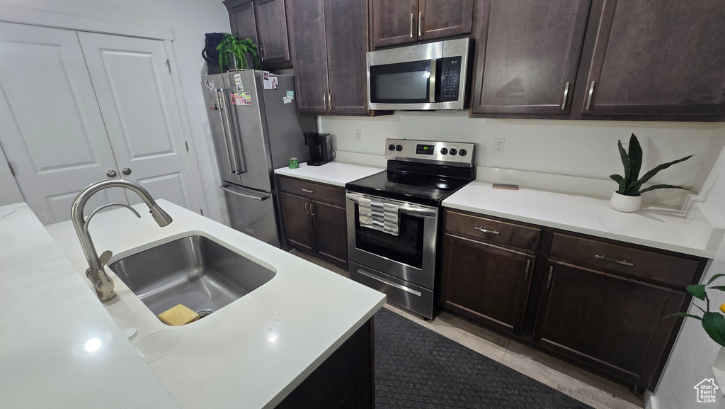 Kitchen featuring appliances with stainless steel finishes, sink, and dark brown cabinets