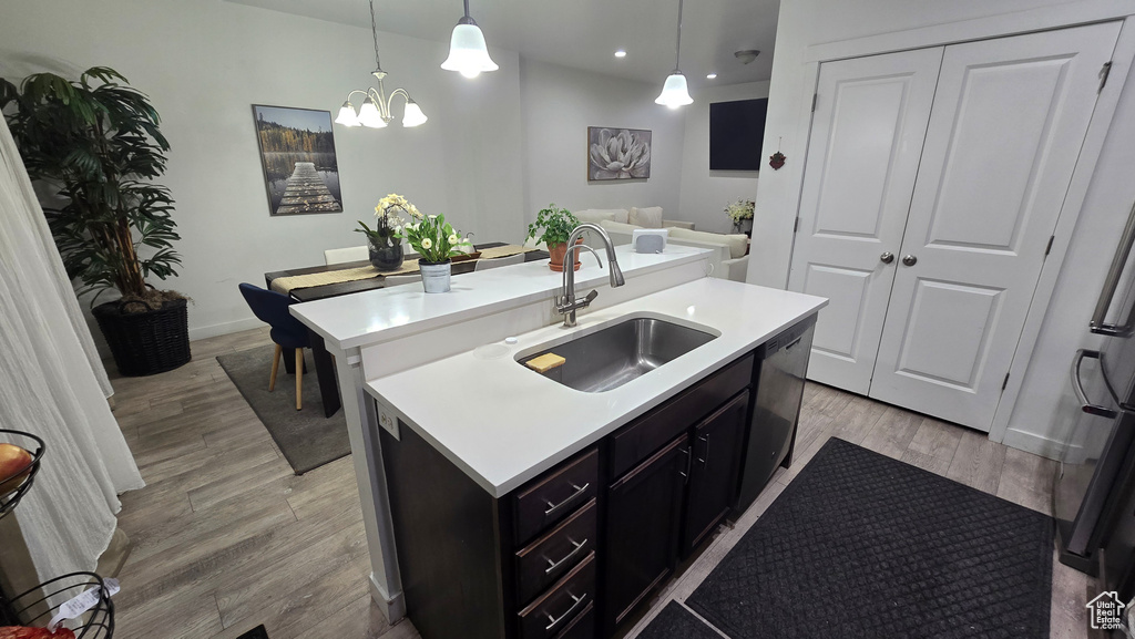 Kitchen featuring pendant lighting, sink, light hardwood / wood-style floors, and a center island with sink