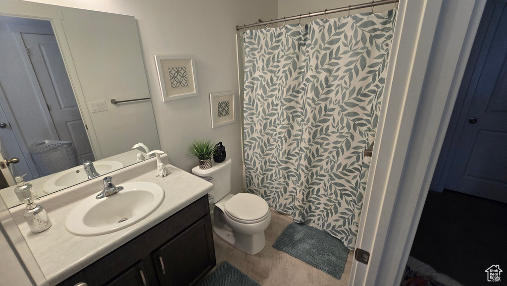 Bathroom featuring vanity, curtained shower, and toilet