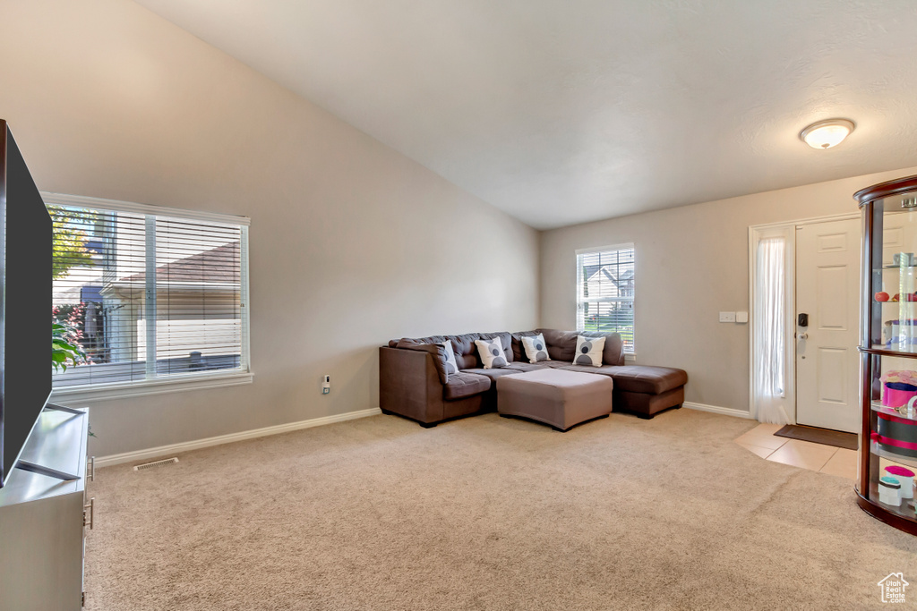 Living room with lofted ceiling and light colored carpet