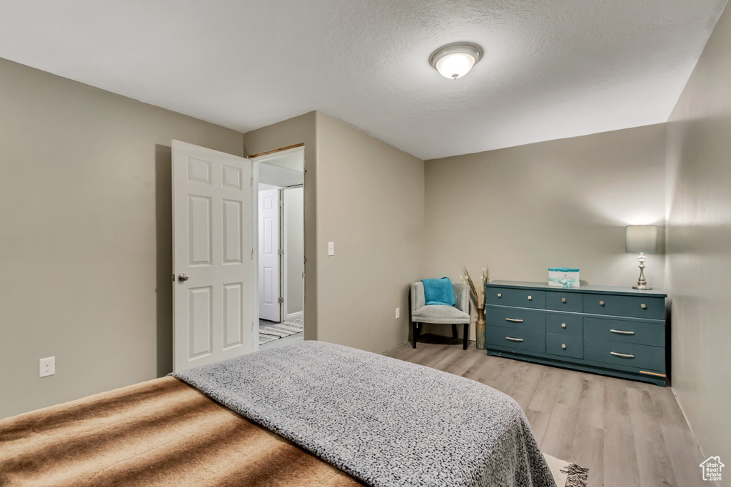 Bedroom with light hardwood / wood-style flooring and a textured ceiling