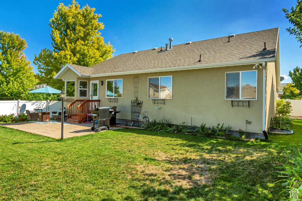 Rear view of house with a yard and a patio