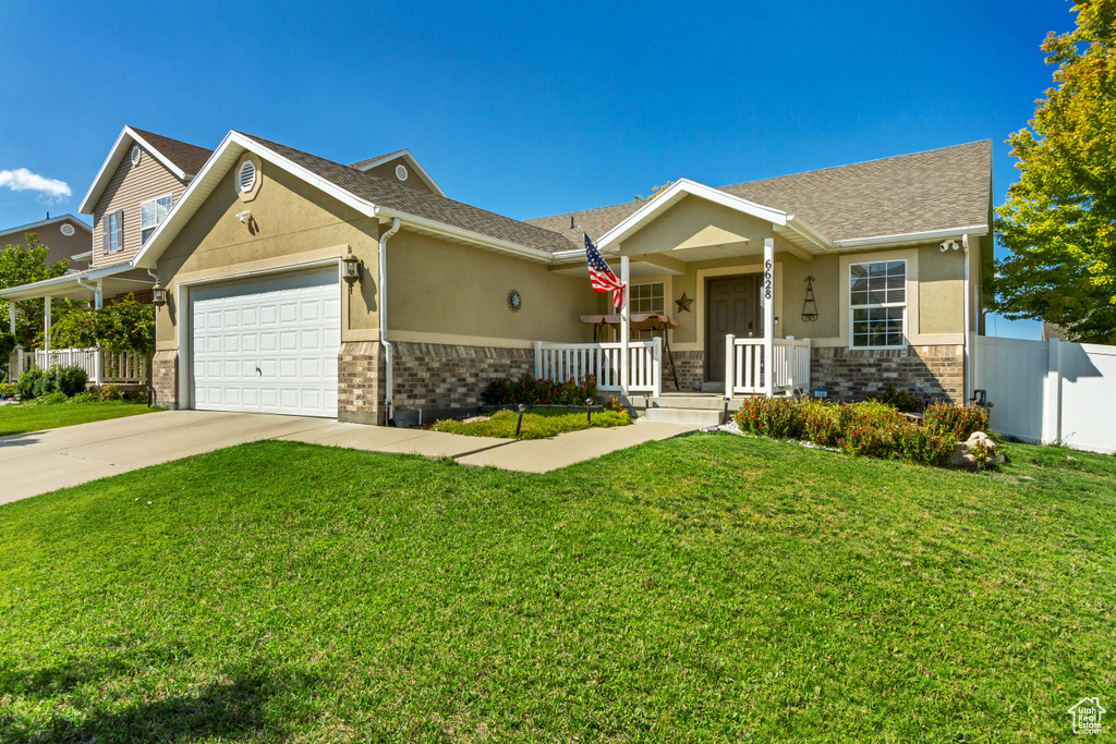 View of front of house featuring a porch, a garage, and a front lawn