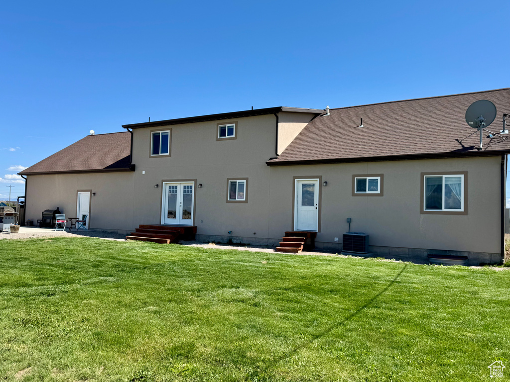 Back of house featuring entry steps, french doors, a lawn, and a shingled roof