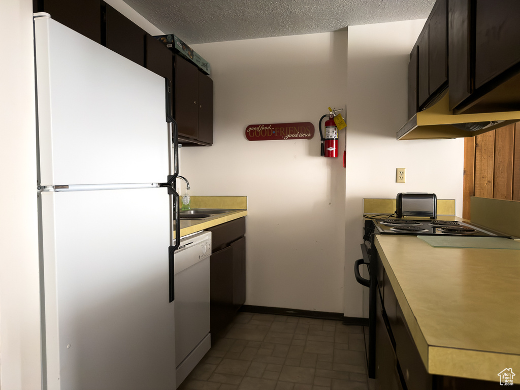 Kitchen featuring white appliances, sink, and a textured ceiling