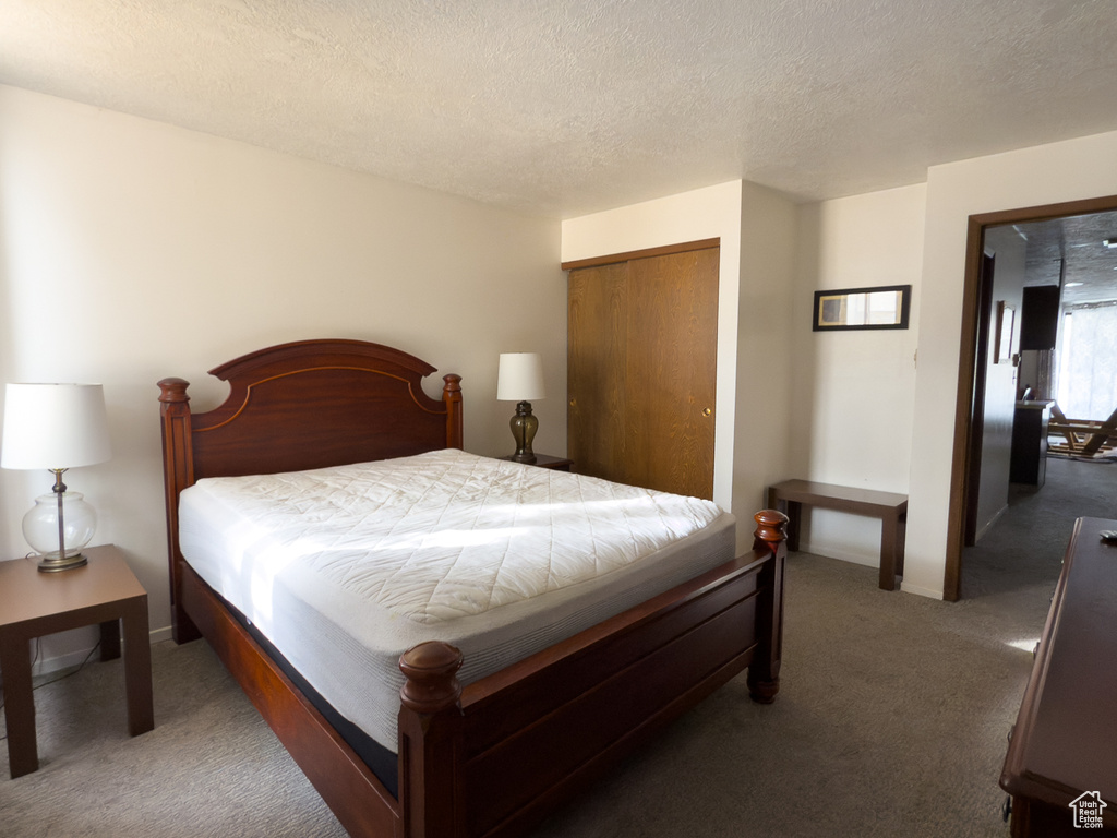 Bedroom featuring dark carpet, a closet, and a textured ceiling