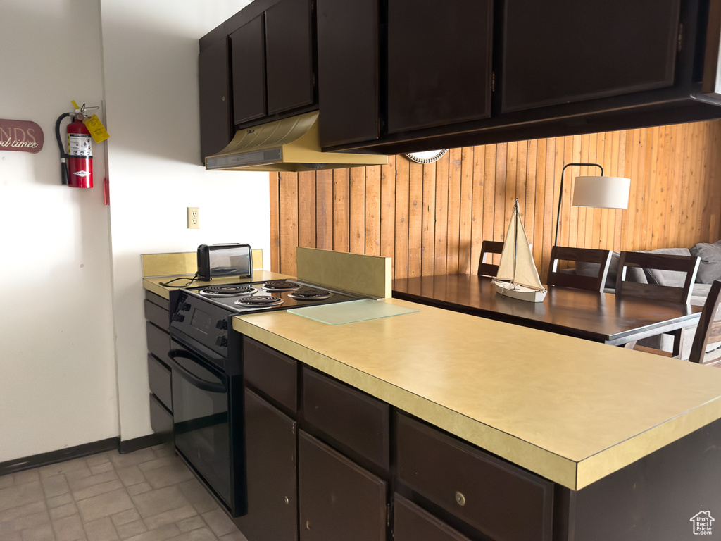 Kitchen with black electric range oven and wood walls