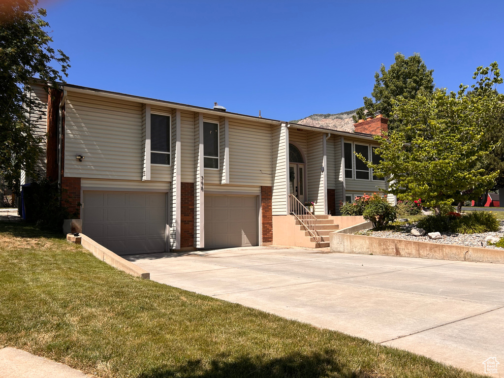 View of front of house with a garage, driveway, a chimney, and a front lawn