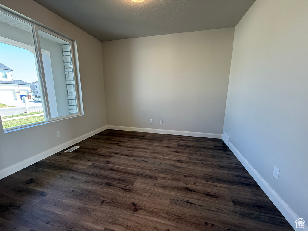 Empty room featuring dark wood-style flooring and baseboards