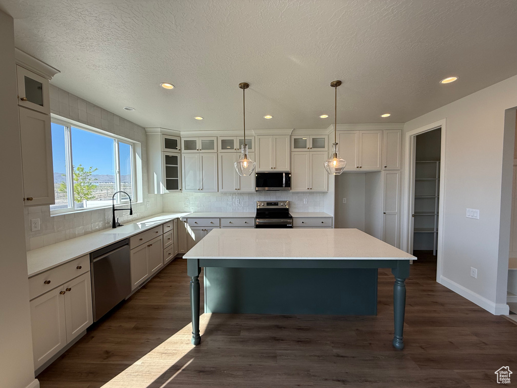 Kitchen featuring appliances with stainless steel finishes, a sink, decorative backsplash, recessed lighting, and a kitchen breakfast bar