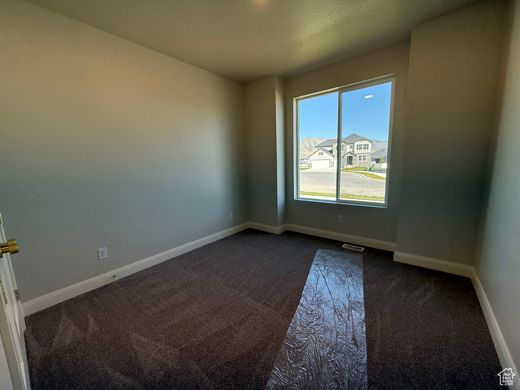 Empty room with dark carpet and baseboards