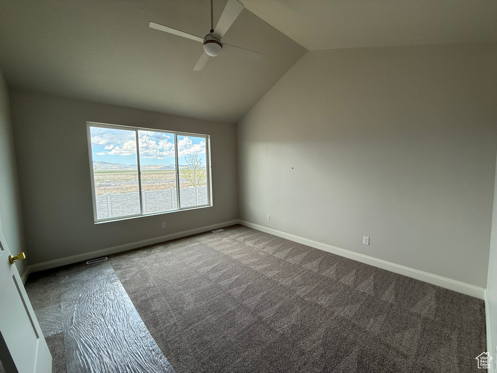 Unfurnished room featuring a ceiling fan, vaulted ceiling, baseboards, and carpet flooring