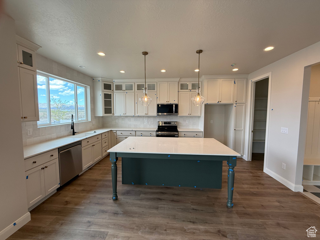 Kitchen featuring appliances with stainless steel finishes, a kitchen breakfast bar, a sink, decorative backsplash, and recessed lighting