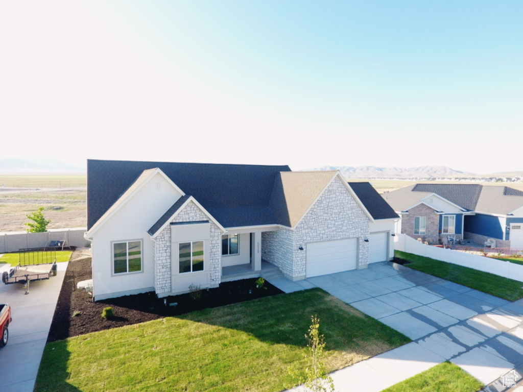 Ranch-style home featuring stone siding, a garage, driveway, and a mountain view