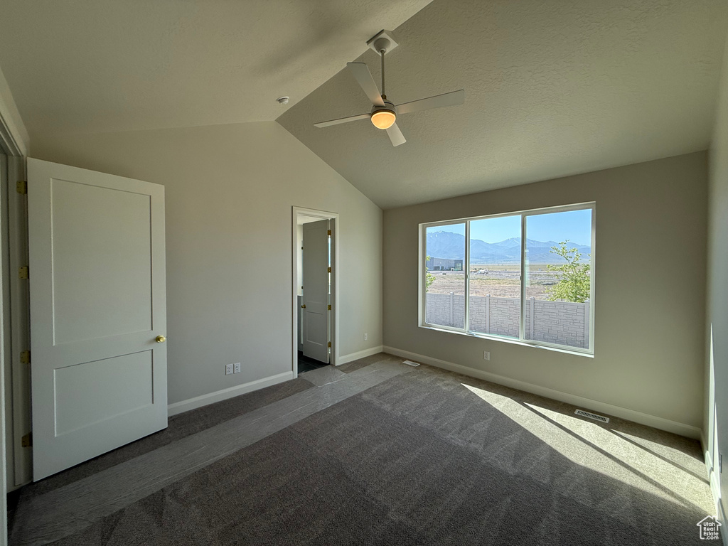 Unfurnished bedroom with carpet flooring, vaulted ceiling, baseboards, a mountain view, and ceiling fan
