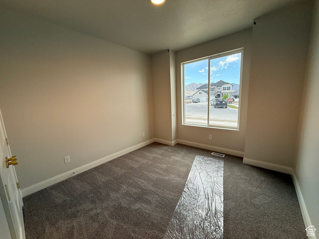 Carpeted spare room featuring baseboards