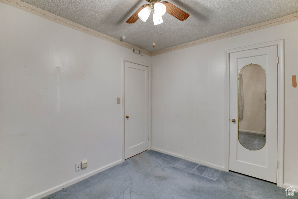 Carpeted spare room with ceiling fan and a textured ceiling