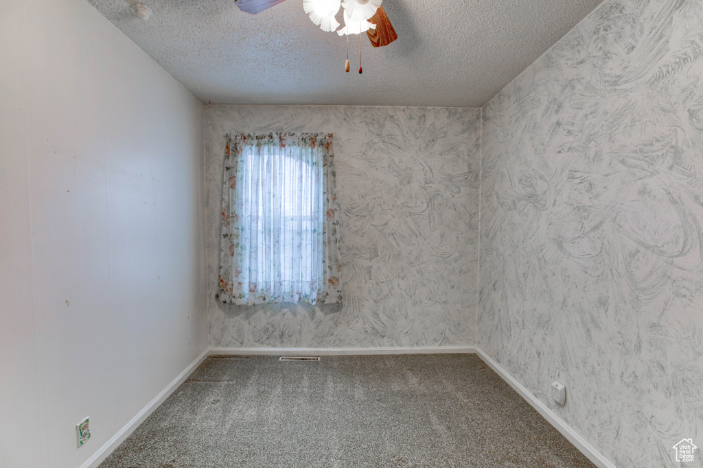 Carpeted spare room with ceiling fan and a textured ceiling