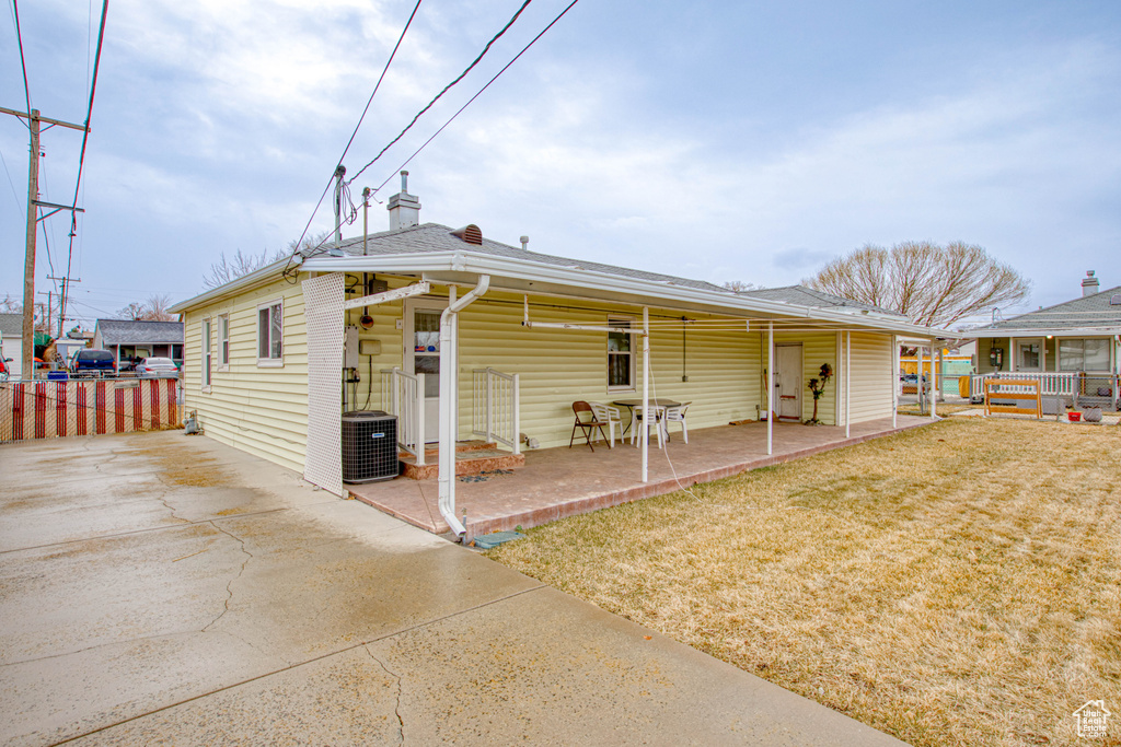 View of front of home featuring a patio, a front yard, and cooling unit