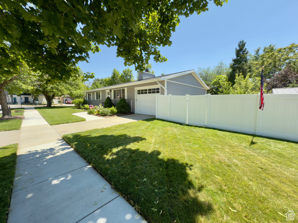 View of front of home with an attached garage, a chimney, and driveway