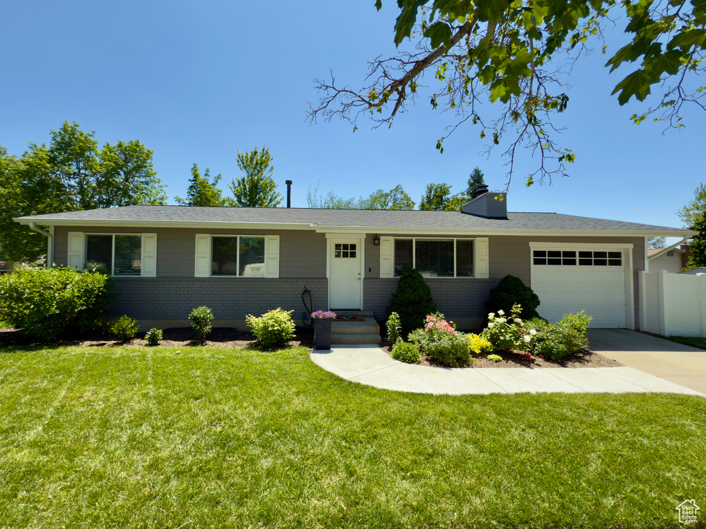 Ranch-style house featuring a garage, brick siding, and driveway