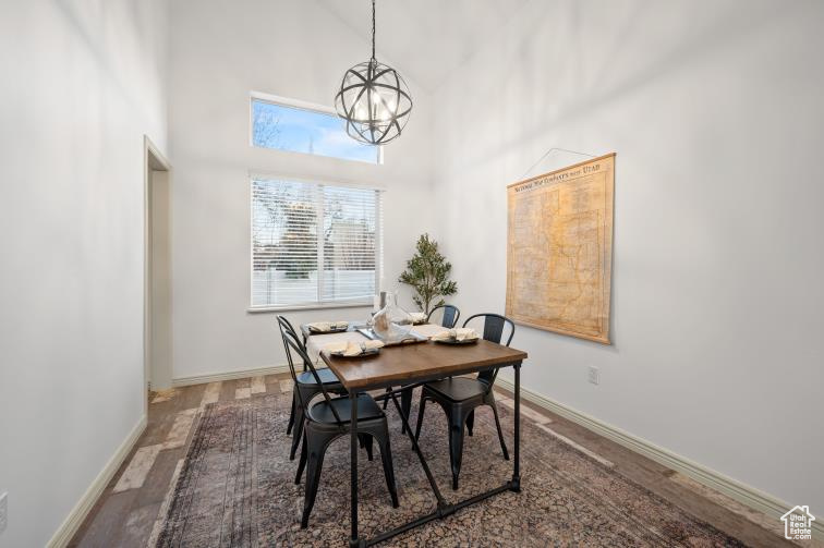 Dining area featuring a chandelier, baseboards, a towering ceiling, and wood finished floors