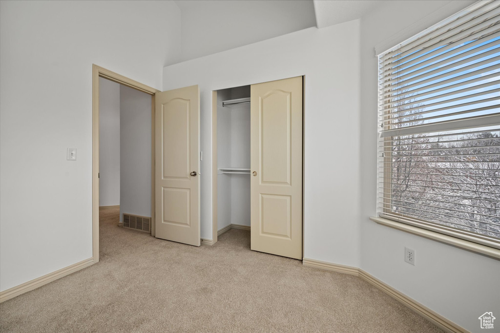 Unfurnished bedroom with light colored carpet and a closet